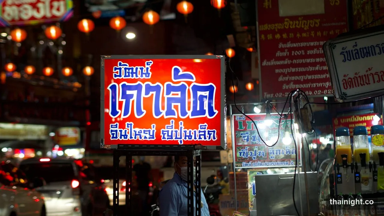 Lit food stall and Thai signage on a Bangkok street at night