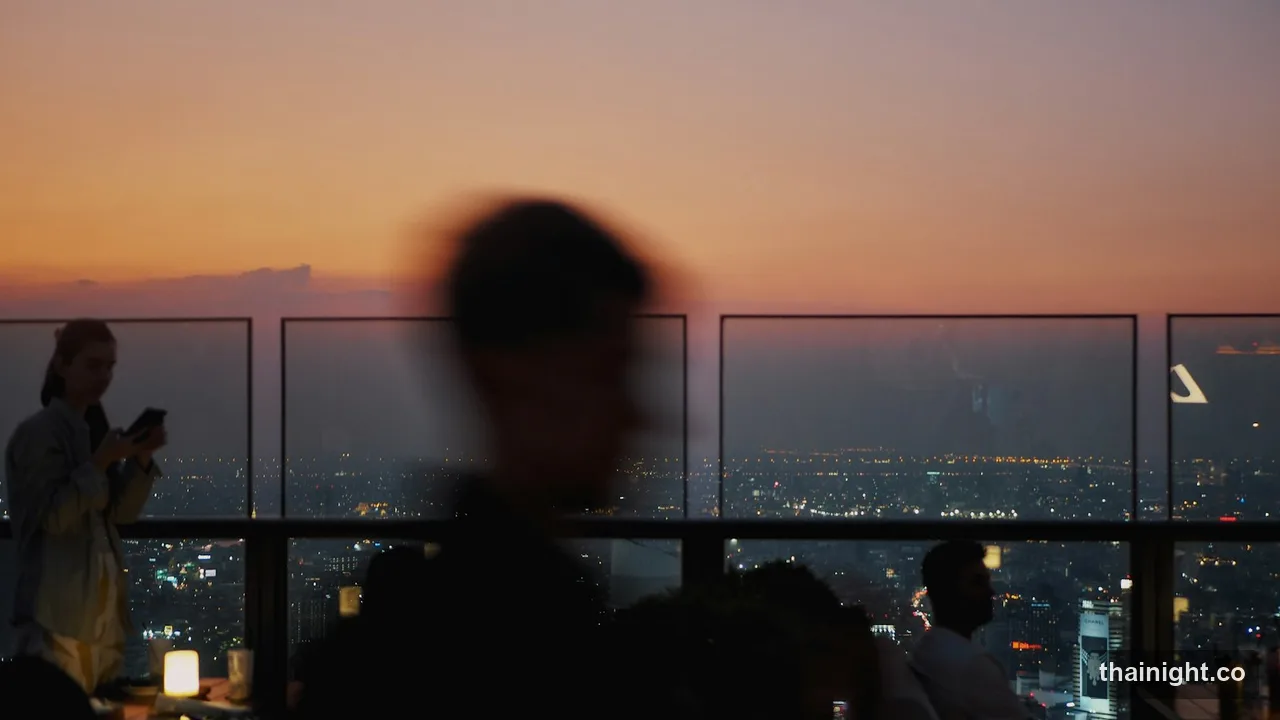 Rooftop bar at sunset in Bangkok, city lights below the terrace