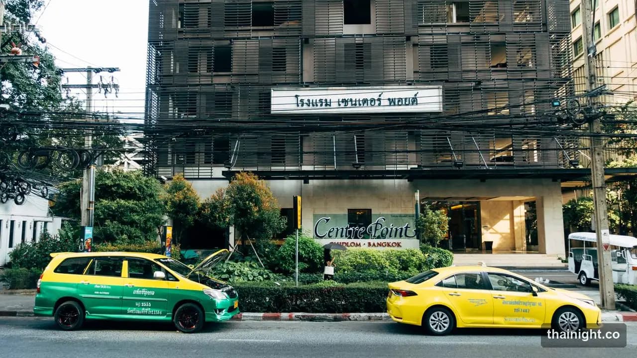 Green-and-yellow and all-yellow metered taxis parked on a Bangkok street